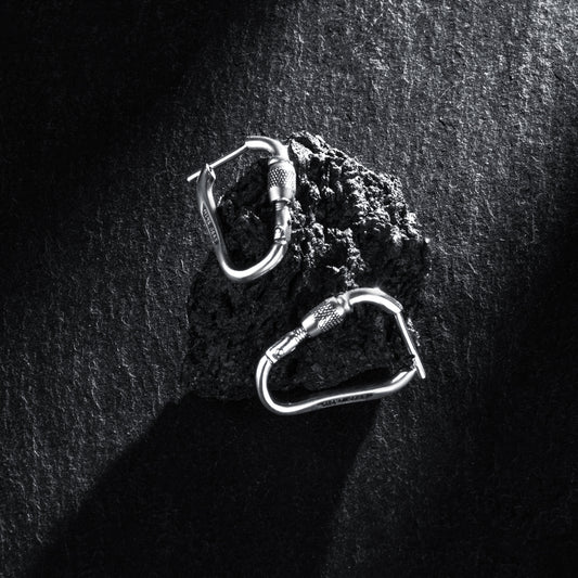 MiniGear Kletterkarabiner-Ohrringe aus 925er Sterlingsilber auf dunklem Hintergrund
